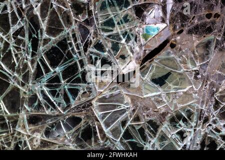 Cracked glass pane in green and brown with ceramic shards. Stock Photo