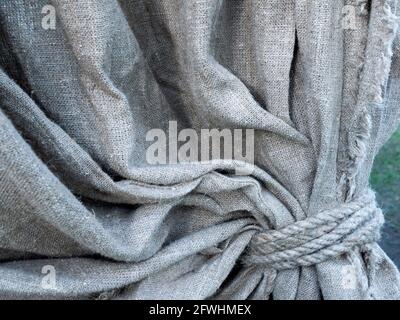 Detail of grey textured linen curtain. Concept of drapery, decoration by the coarse rustic cloth Stock Photo