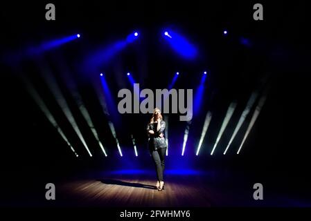 pretty woman artist over the background of blurred spotlights on the stage Stock Photo