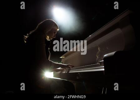 Close up view of a girl plays piano in the concert hall at scene Stock Photo