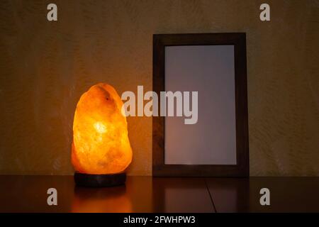 Himalayan pink salt lamp on wood table and photo frame. Home health therapy and fond memories. Stock Photo