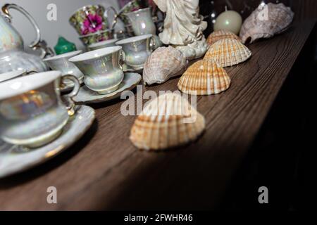 Household items on a sideboard shelf behind glass. Tourist souvenirs, cups, shells. Stock Photo