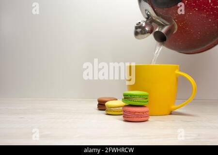 macaroons on the background of a yellow cup and teapot Stock Photo