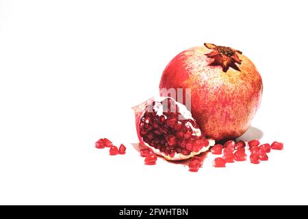 One ripe red pomegranate and a piece of pomegranate with grains on a white background Stock Photo