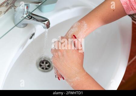 the girl washes her hands in the bathroom over the sink Stock Photo
