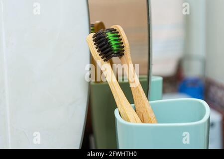 2 kissing toothbrushes in a cup against the background of a mirror. Stock Photo