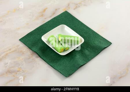 Melon and lime chewy candy pieces in white candy dish on green paper napkin Stock Photo