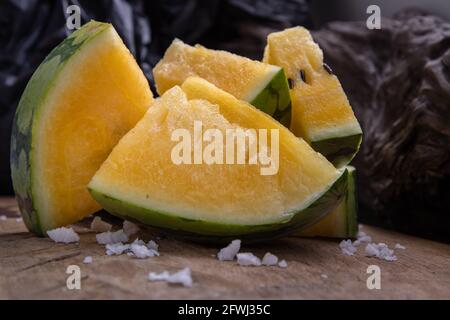 Fresh juicy yellow watermelon cut into triangles on old wooden background. Tropical fruits, Select focus. Stock Photo