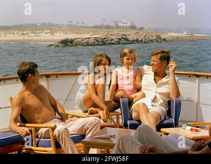 President John F. Kennedy sits with his daughter, Caroline (second from right); brother-in-law, Steve Smith (far left); and niece, Maria Shriver (second from left), aboard the presidential yacht, Honey Fitz, during a cruise near Hyannis Port, Massachusetts. Stock Photo