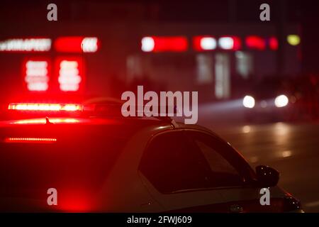 red police car light at night in city with selective focus and blurry car in the background. Stock Photo