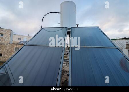 Solar panels that heat water, next to a white water heater. On a roof in Jerusalem Stock Photo