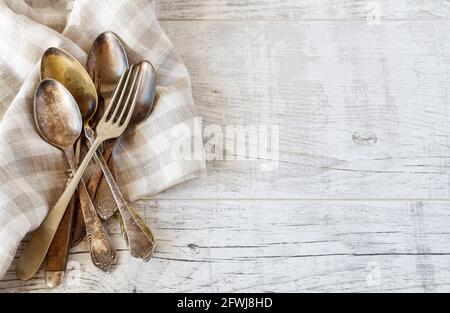 Vintage cutlery and checkered napkin on wooden table, copy space. Stock Photo