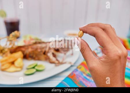 Woman holding a Peruvian corn nut known also as cancha, small appetizer plate . Selective Focus Stock Photo