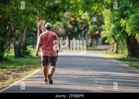 Back view of Fat man jogging or running exercising outdoors in park, Concept of healthy lifestyle. Stock Photo