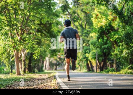 Back view of man jogging or running exercising outdoors in park, Concept of healthy lifestyle. Stock Photo