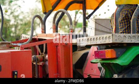 07 May 2021- Reengus, Sikar, India. Bottom view of excavator flipping the bucket of red color loaded with organic fertilizer on blue cloudy sky backgr Stock Photo