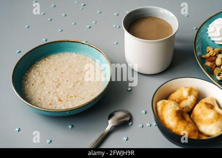 Bright breakfast on gray background, top view. Tasty oatmeal, croissants and cup of coffee. Stock Photo