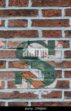 A green letter s painted on a red brick wall Stock Photo