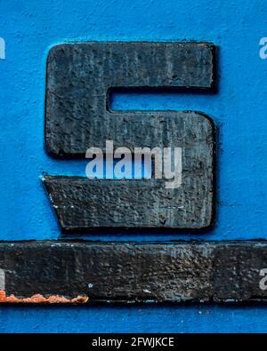 Black metal letter S with black underline on blue background Stock Photo