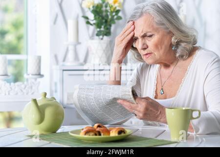 Portrait of a senior woman reading newspaper Stock Photo