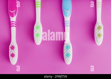 Four toothbrushes on a pink background in a row. Free space, isolate, top view Stock Photo
