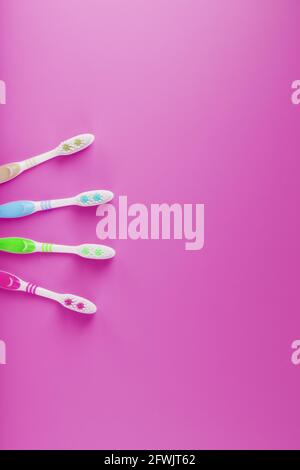 Four toothbrushes on a pink background in a row. Free space, isolate, top view Stock Photo