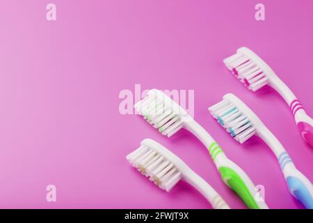 Four toothbrushes on a pink background in a row. Free space, isolate, top view Stock Photo