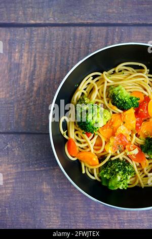 Healthy home cooking: Spagetthi with vegetables (brokkoli, tomatoes, carrots) in a frying pan. Stock Photo
