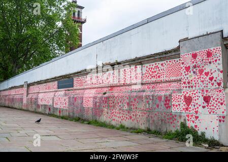 National Covid Memorial Wall on a grim overcast day in Lambeth, London, UK. Red hearts drawn onto a wall representing each death from COVID 19. Bird