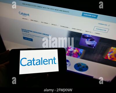 Person holding smartphone with logo of American pharmaceutical company Catalent Inc. on screen in front of business webpage. Focus on phone display. Stock Photo