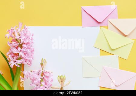Colorful envelopes and hyacinth flowers on yellow background, copy space. Stock Photo