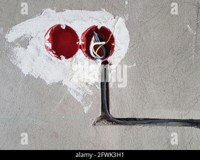 Electrical wires with cables at home repair. New electrical outlets. Socket on concrete wall Stock Photo
