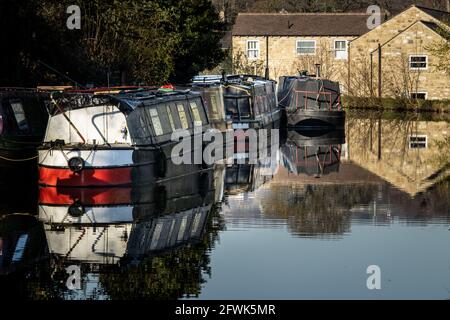 An early morning walk along the Leeds & Liverpool canal in springtime with moored barges opposite the towpath at Apperley Bridge, Yorkshire Stock Photo