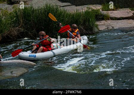 Tokovsky waterfall, Kamenka river, Ukraine - 05.16.2021: Concept of active recreation. A group of young people is rafting down the river. Stock Photo