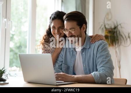 Smiling sincere married couple web surfing information online. Stock Photo