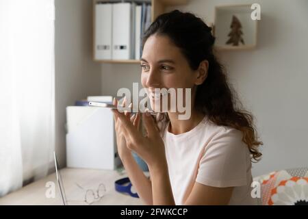Happy young hispanic woman recording audio message on cellphone. Stock Photo