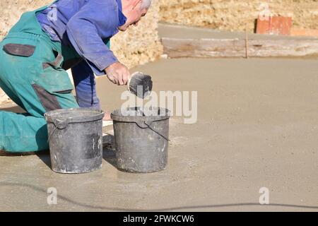 The mason pours fresh concrete poured on the foundation wall Stock Photo