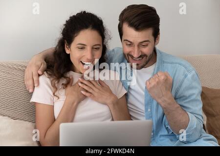 Happy young family couple celebrating online lottery win. Stock Photo