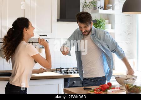 Happy young family couple having fun together in kitchen. Stock Photo