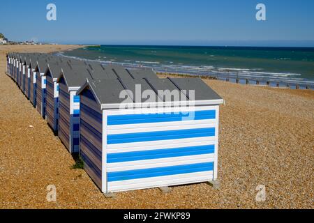 Staycation idea. Row of Blue and White Stripped Beach Huts on Hastings Beach, East Sussex, England, UK. Stock Photo