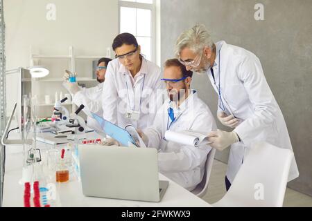 Group of scientists working in laboratory, doing research and discussing data reports Stock Photo