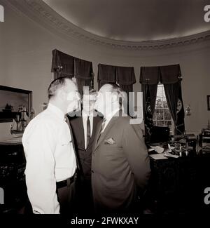 President John F. Kennedy laughs during a visit with actor and comedian, Bob Hope (at right, facing White House Police officer, Private Robert Suggs, Jr.), in the Oval Office of the White House, Washington, D.C. Mr. Hope visited the White House to receive the Congressional Gold Medal, presented by President Kennedy in recognition of his services to the country as an entertainer during World War II. Stock Photo