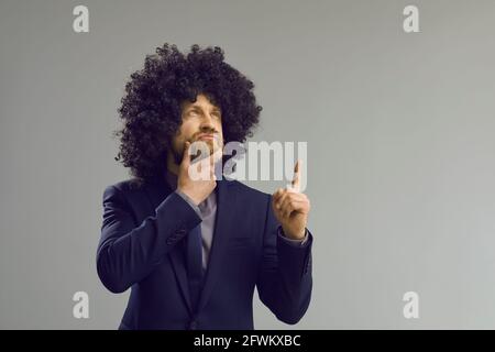 Caucasian hipster man in funny curly afro hair wig thinking and brainstorming Stock Photo