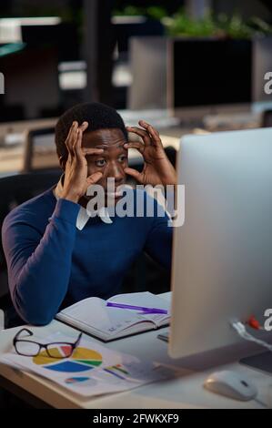 Tired young manager works in night office Stock Photo