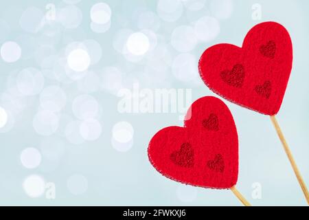 Two red heart decoration on wooden stick on light blue shining background with copy space, romance or Valentine background Stock Photo