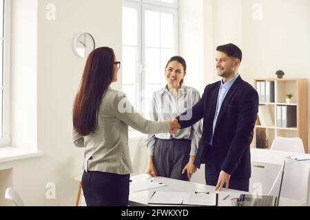 Bank worker, financial advisor or credit broker shaking hands with happy young couple Stock Photo
