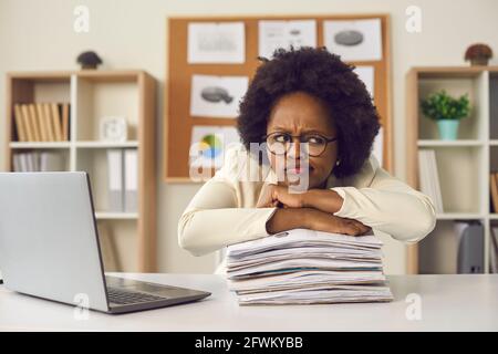 Young frowning busy african american woman employee sitting at office table Stock Photo