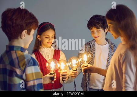 School children joining idea light bulb together standing in circle studio shot Stock Photo
