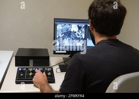 Young man scientist working with scanning electron microscope. Laboratory technician observing samples with a SEM. Stock Photo