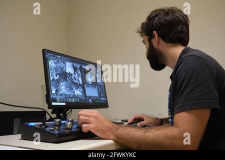 Young man scientist working with scanning electron microscope. Laboratory technician observing samples with a SEM. Stock Photo